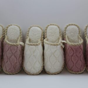 Five pairs of cozy knitted slippers in pink and white.